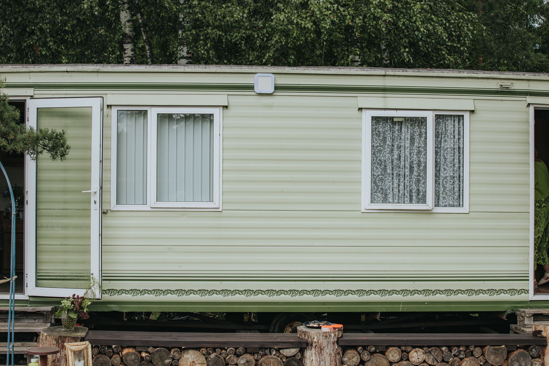 Mobile home exterior with light vinyl siding panels and green trim accents.