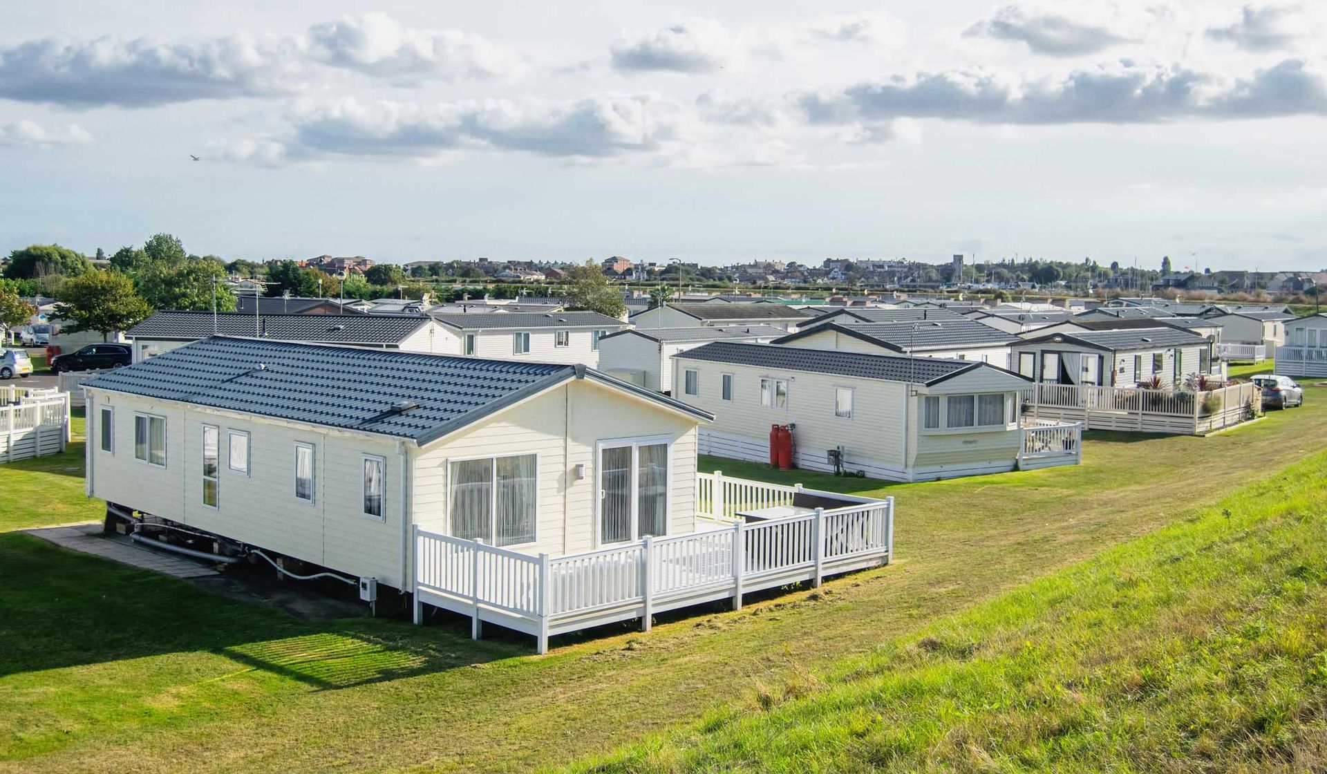 A row of modern mobile homes with decks set on a grassy hillside