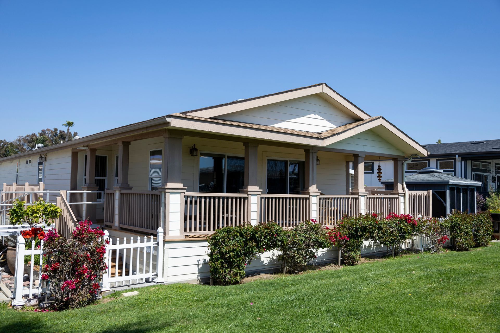 A yellow and brown prefabricated home in a trailer park under a clear blue sky