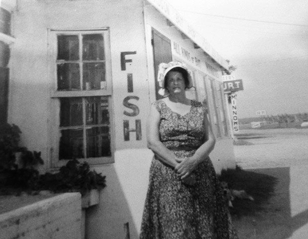 A woman stands in front of a fish shop