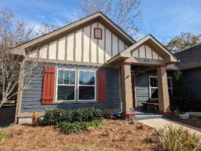 Gray house with red shutters, tan trim, and a small porch.