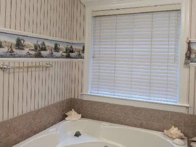 Bathroom with a window, tub, seashell decorations, and striped wallpaper with a nautical border.