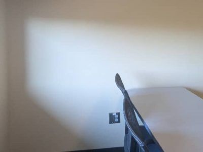 A chair angled towards a white table, against a white wall with an electrical outlet.