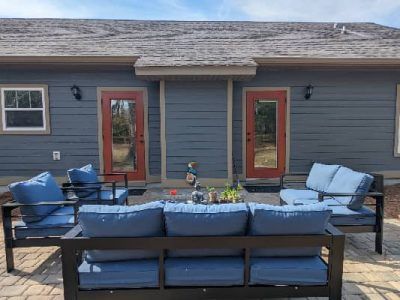 Blue outdoor furniture on a patio in front of a blue house with two red doors.