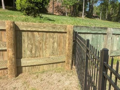 Wooden fence with dark brown posts and green panels, connecting to a black metal fence.