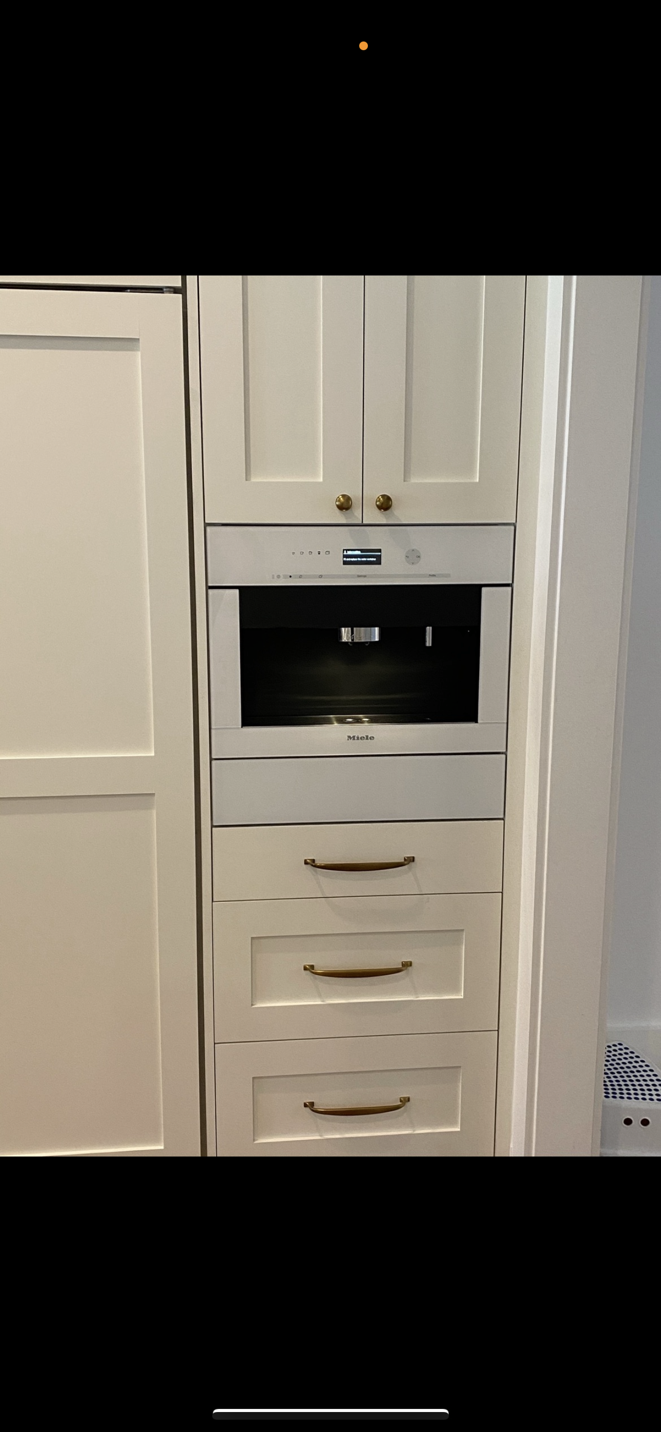 A kitchen wall cabinet featuring a built-in oven, three storage drawers below, and upper cabinets, all in white.