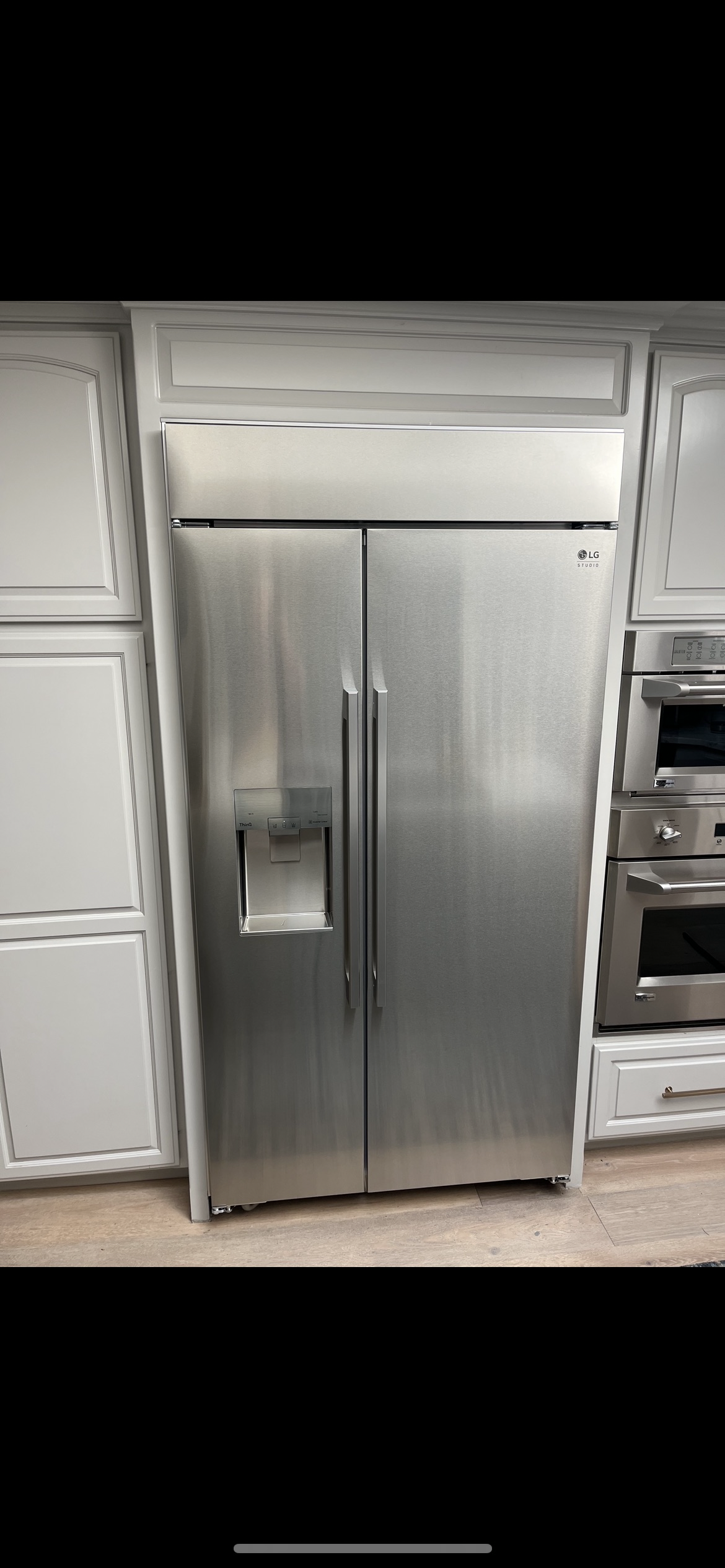 A stainless steel refrigerator freezer is sitting in a kitchen.