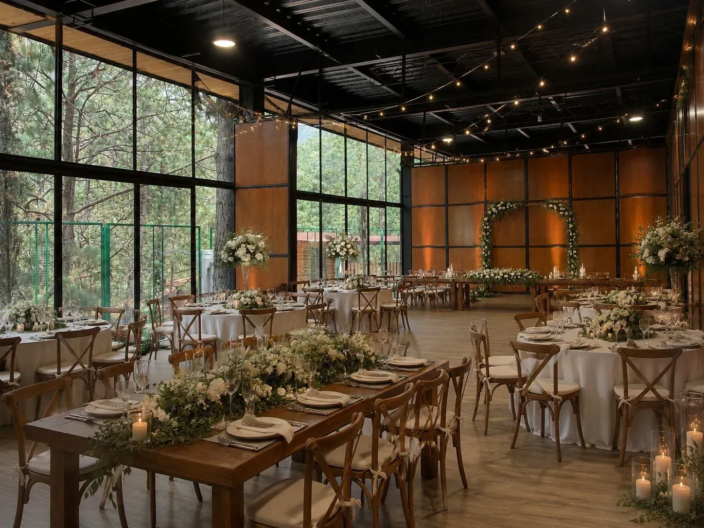 Elegante decoración para  evento en interiores, con mesas ,flores, velas y  ventanales con vista al bosque