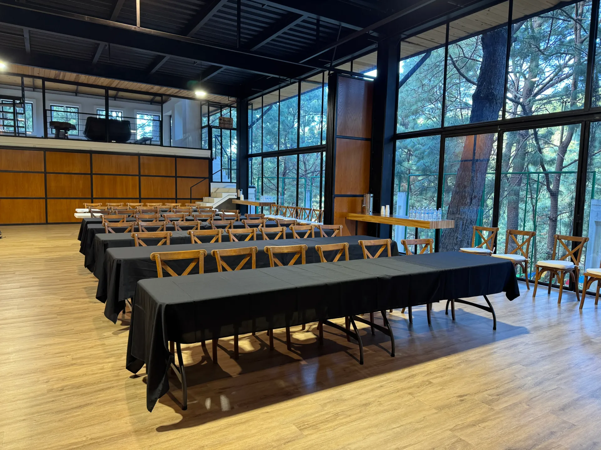 Sala de conferencias con mesas y sillas largas en un moderno espacio para eventos con paredes de cristal.