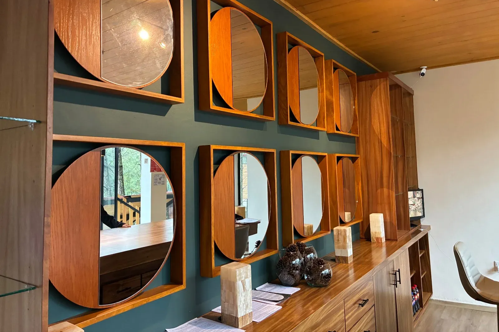 Interior moderno con estantes de pared geométricos de madera, espejos y una encimera de madera en tonos cálidos.