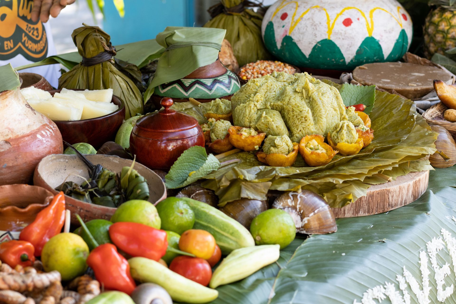 Surtido colorido de ofrendas de comida tradicional dispuestas sobre hojas verdes y bandejas de madera.