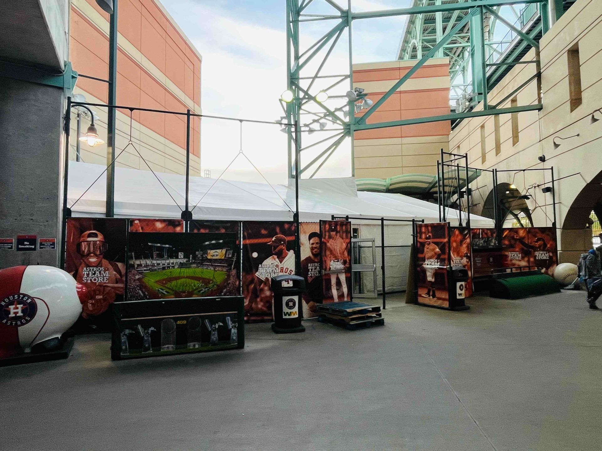 Astros merchandise display at stadium with tents, posters, and a large helmet.