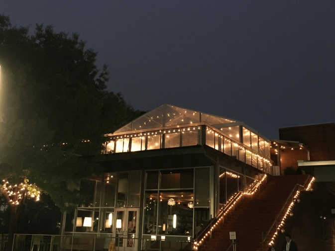Restaurant at night with string lights, a clear tent, and a red carpet stairway.