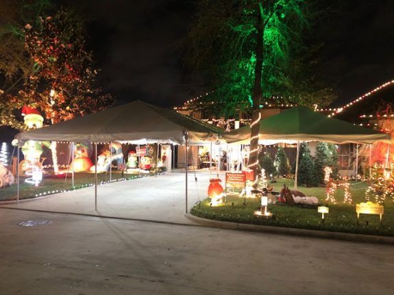 Holiday display with tents set up on a driveway, lit with colorful lights and decorations at night.