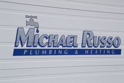 Michael Russo Plumbing & Heating logo on a white wall, with blue text and a faucet icon.