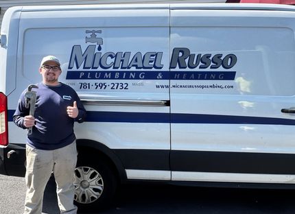Man standing beside a Michael Russo Plumbing Service van with blue lettering and logo