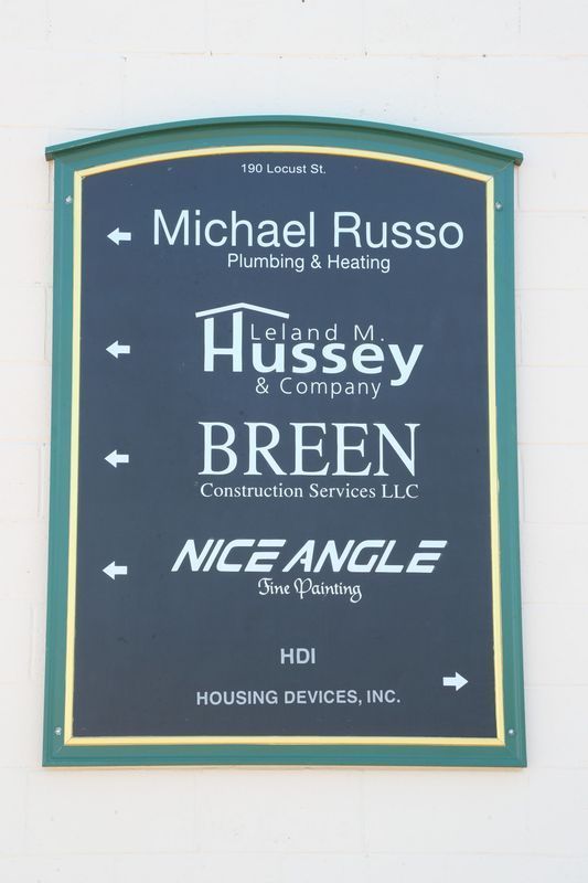 Blue sign listing business names in white text, including Michael Russo, Hussey, Breen, and Nice Angle.