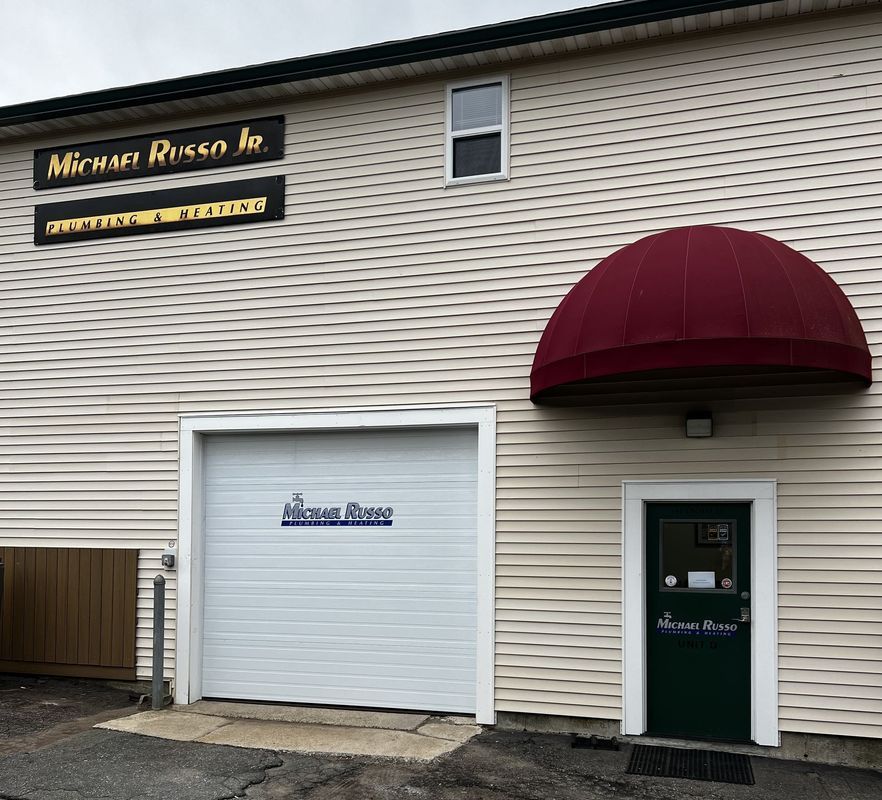Building exterior with beige siding, burgundy awning, white garage door, and dark green entry door.