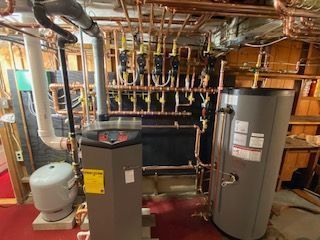 Basement utility room with water heater, boiler, pipes, and ductwork.