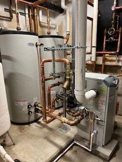 Basement mechanical room with water heater, furnace, copper pipes, and ductwork