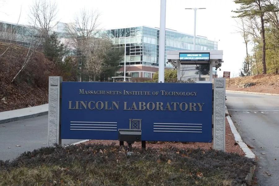 Blue Lincoln Laboratory sign beside a road at a Massachusetts Institute of Technology campus entrance