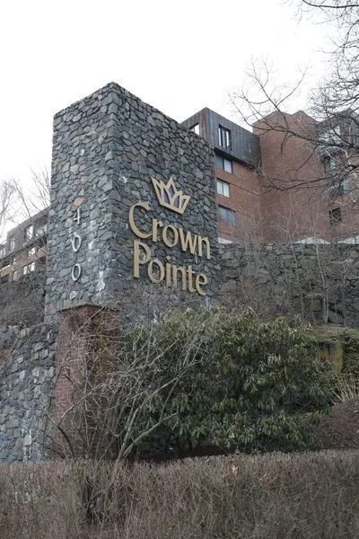 Stone sign reading “Crown Pointe” beside apartment buildings and leafless trees
