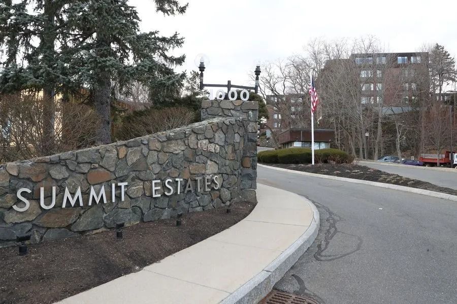 Stone entrance sign reading “Summit Estates” beside a curved driveway and trees.