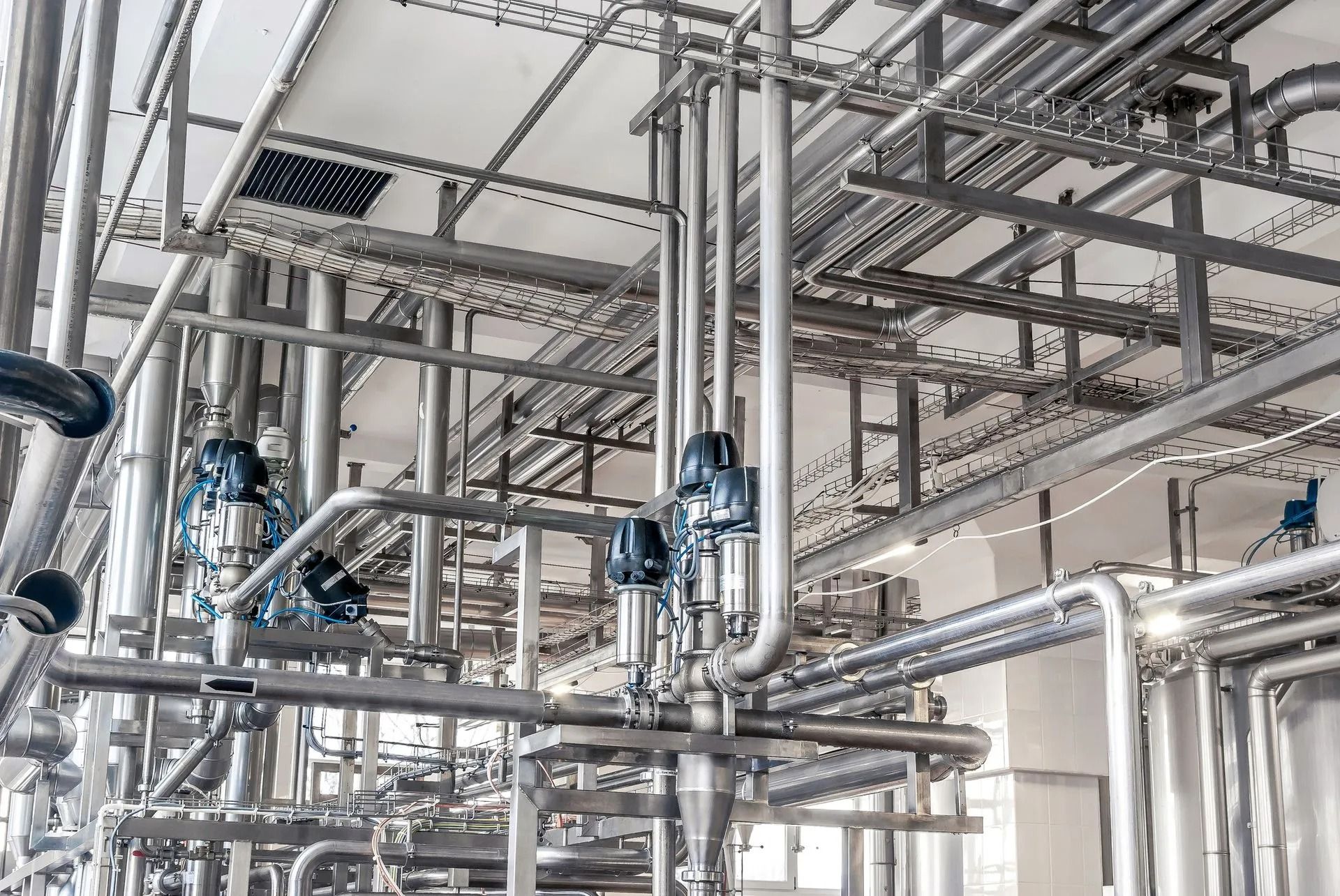 Stainless steel industrial piping and valves in a bright factory interior