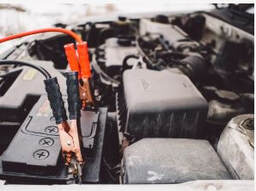 Picture of a dead battery with jumper cables hooked up to it.
