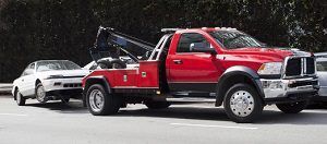 Picture of a red Vancouver tow truck towing a white car.