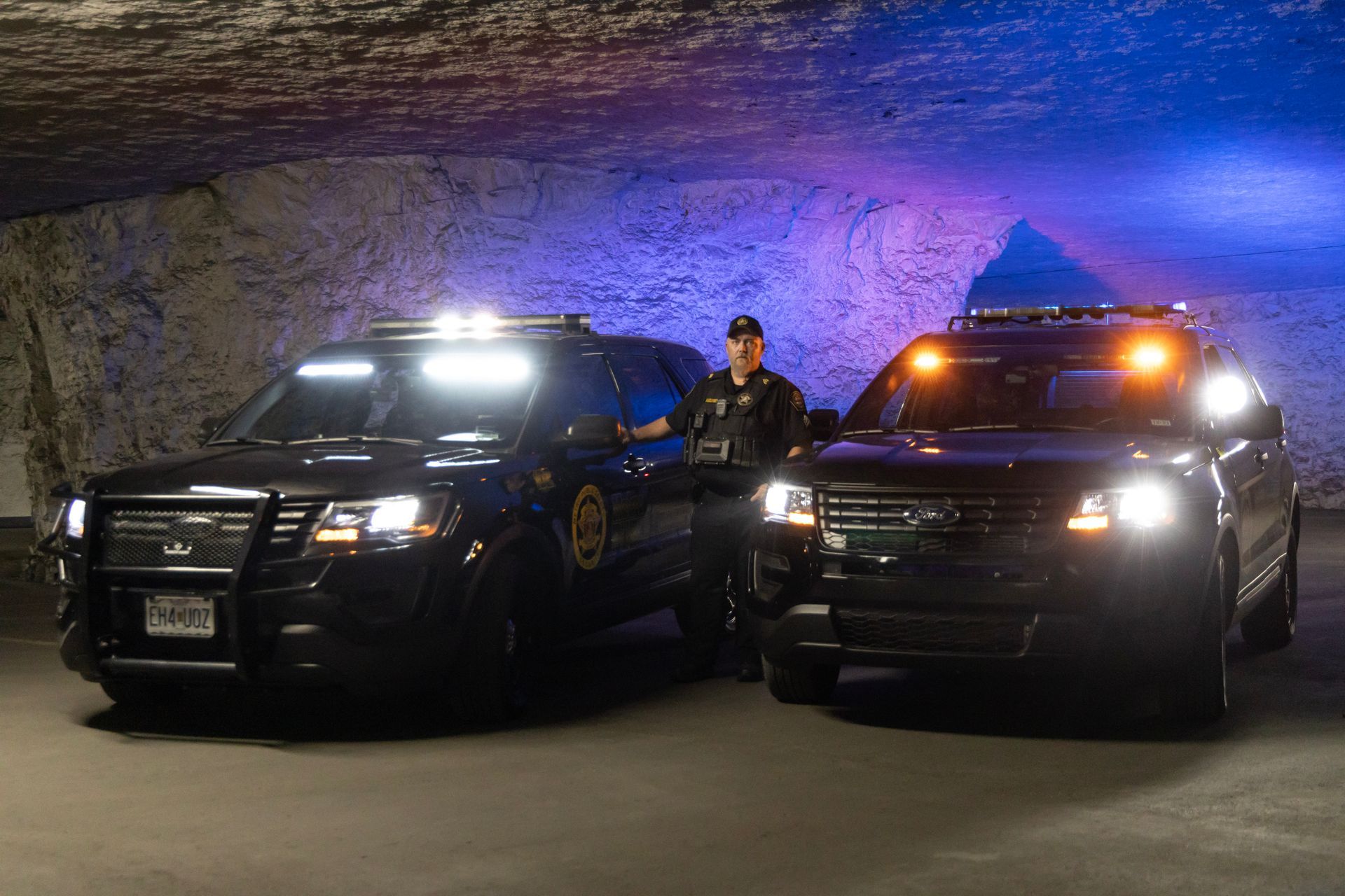 Two police cars are parked next to each other in a dark room.