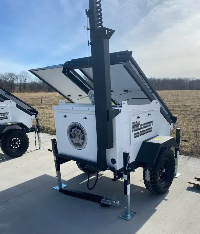 A white camera trailer with a black pole on top of it