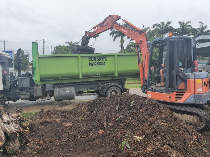 Excavator Loading Soil Into a Green Dump Truck — Eco Skips In Midge Point, QLD