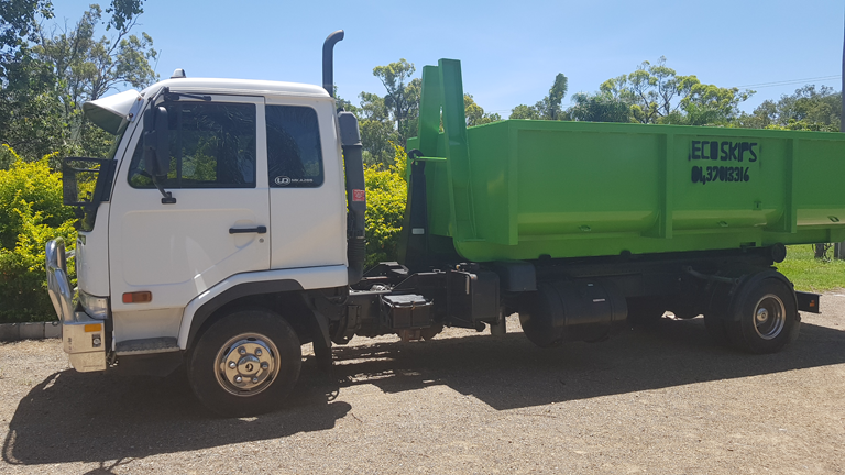 White-and-green Dump Truck Parked on a Dirt Lot in Bright Sunlight — Eco Skips In Midge Point, QLD