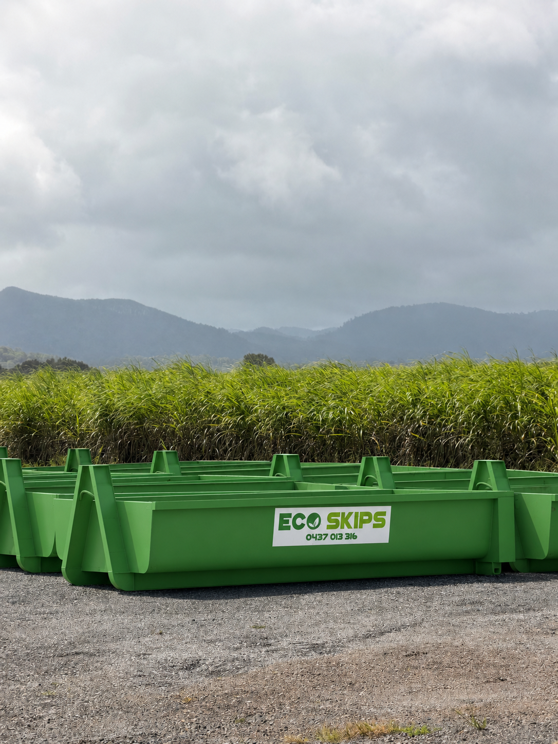 Green Recycling Bins on a Gravel Lot With Mountains — Eco Skips In Midge Point, QLD