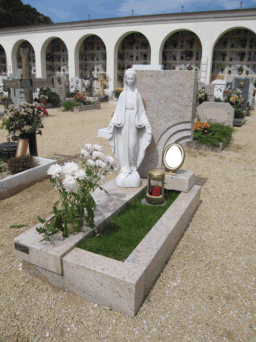 Una tomba in un cimitero con una statua di Maria sopra