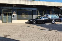 Un carro funebre nero è parcheggiato davanti a un edificio.