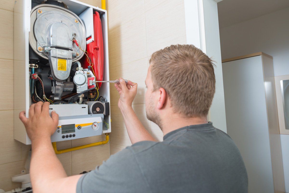 Technician Repairing Gas Furnace — Lexington, KY — High Vac Services! Technician Repairing Gas Furnace — Lexington, KY — High Vac Services!
