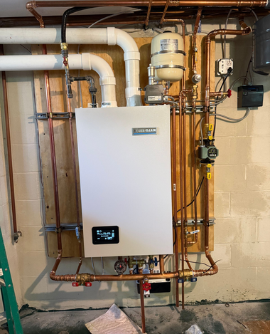 Wall-mounted white boiler and copper pipes in a basement utility area