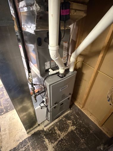 Basement furnace and ductwork beside a wall, with white PVC pipes and exposed insulation.