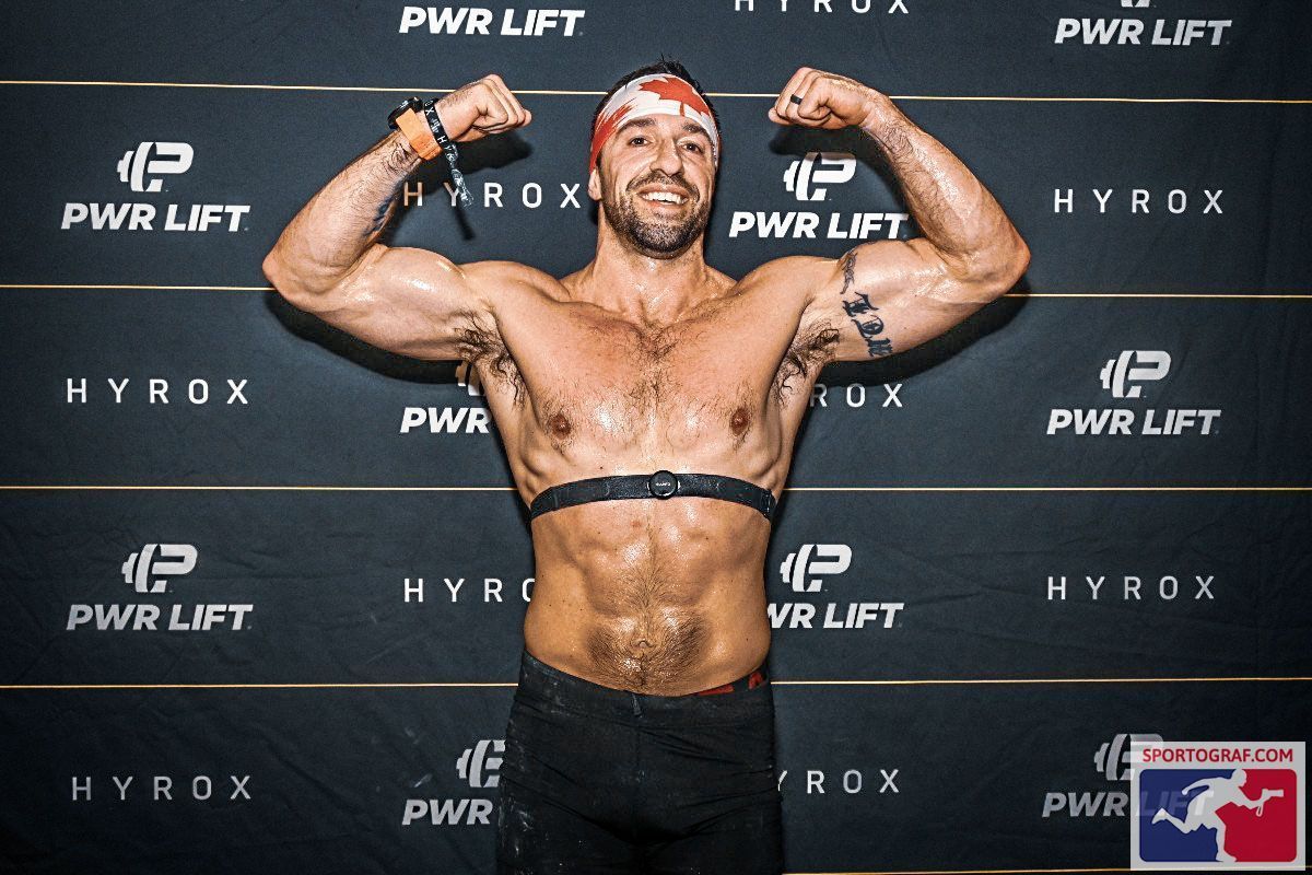 Un homme contracte ses muscles devant un mur sur lequel est écrit pwr lift