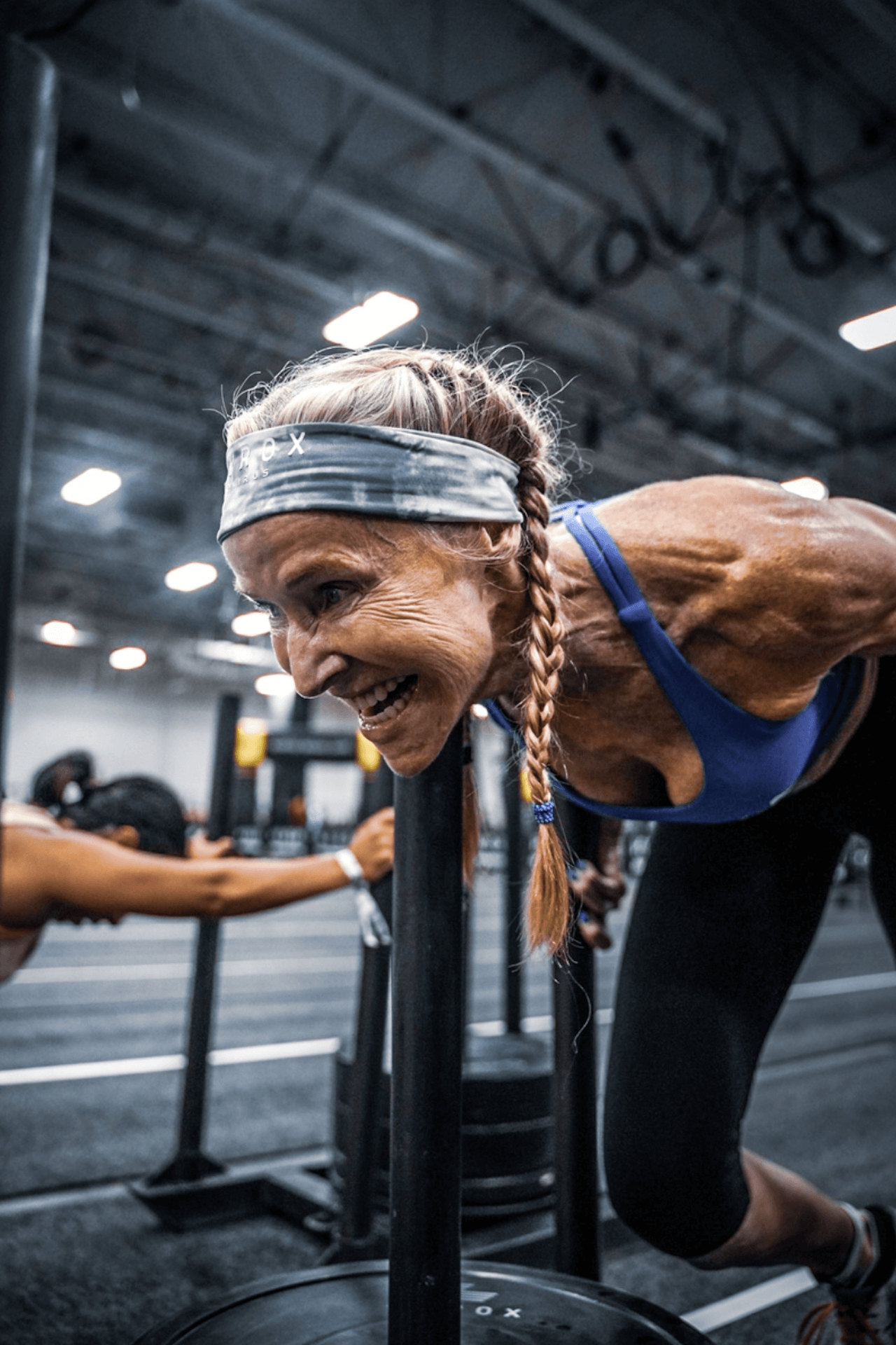Une femme pousse un traîneau dans une salle de sport.