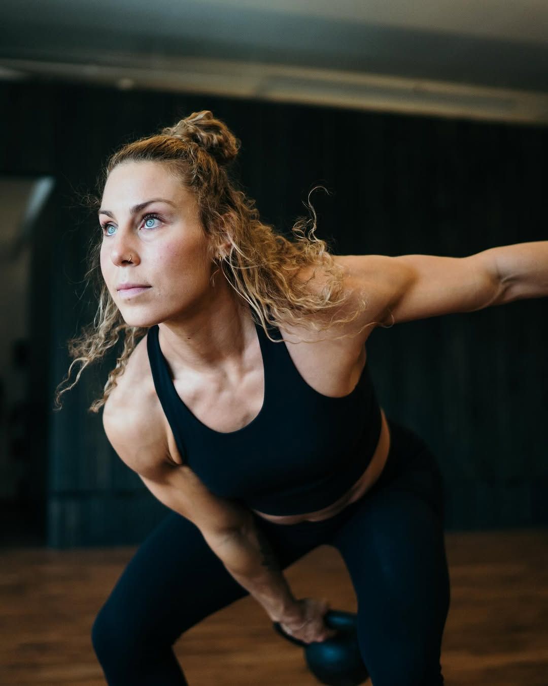 Une femme soulève une kettlebell dans une salle de sport.