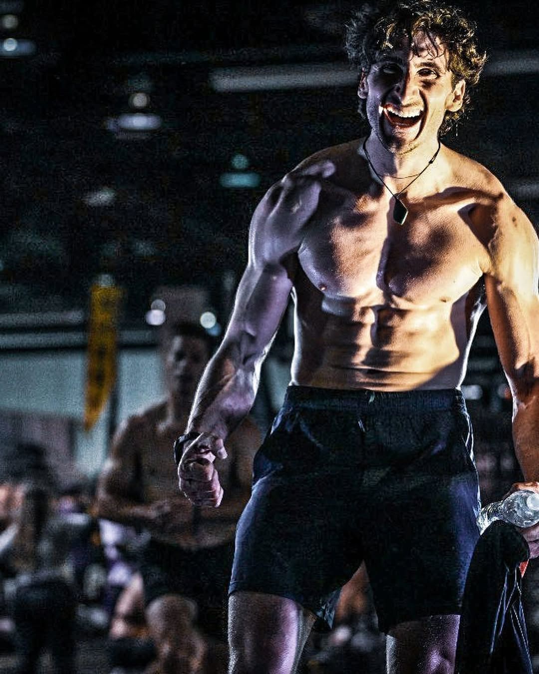 Un homme sans chemise se tient debout dans une salle de sport