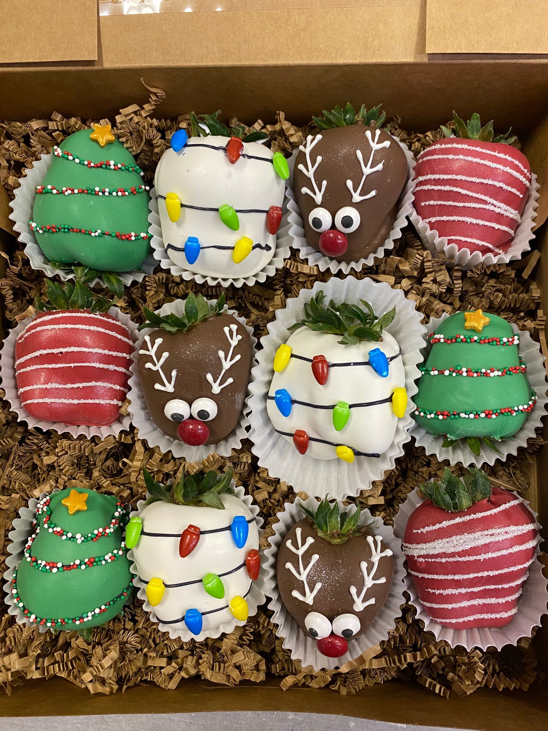 Assorted festive decorated cookies in a box, green, red, white, and reindeer designs with holiday sprinkles