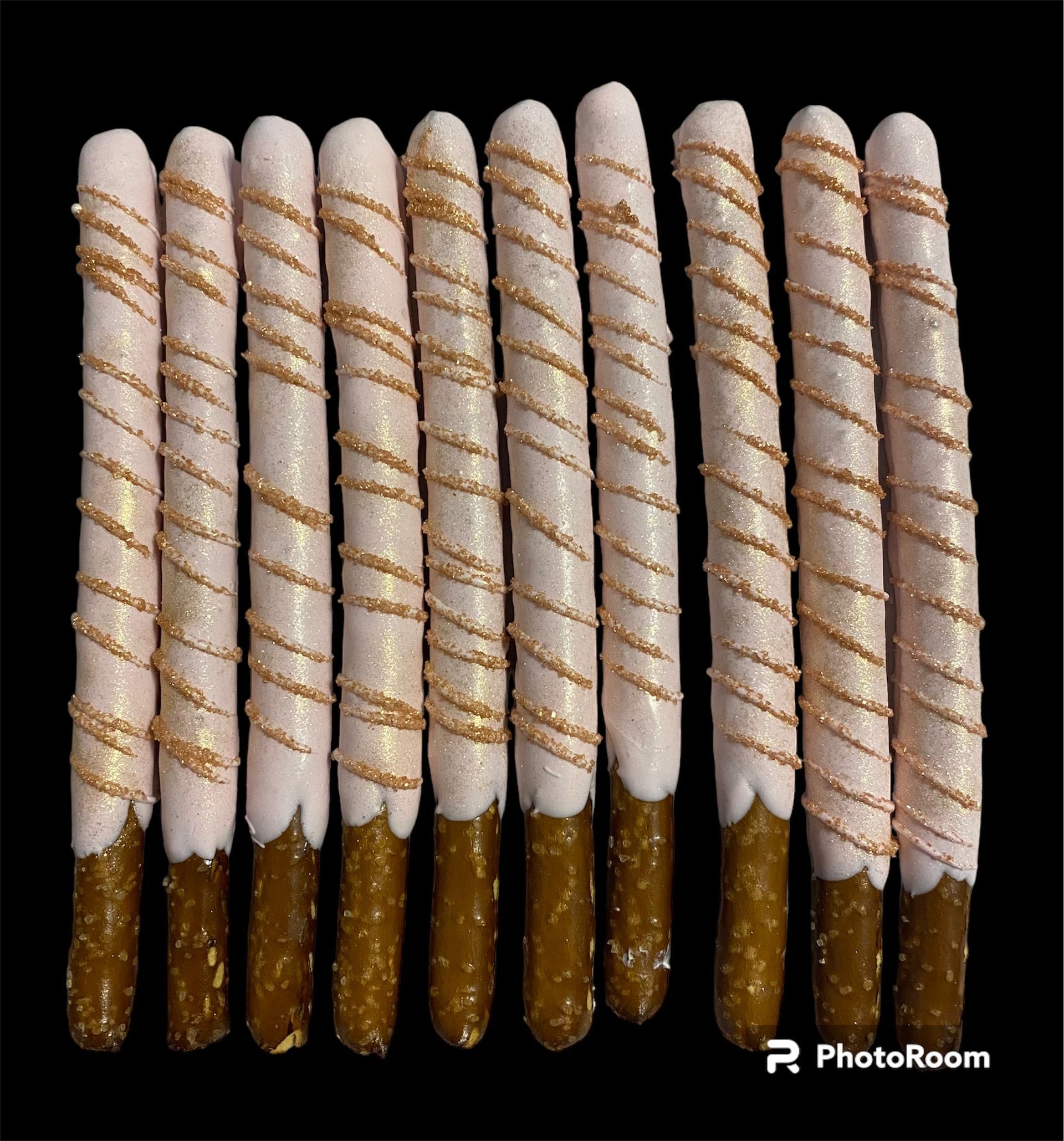 Eight white-and-brown chocolate-dipped pretzel sticks arranged in a row on a black background