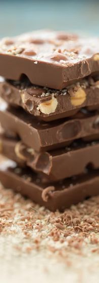 Stack of chocolate bars with caramel and nougat filling, topped with chocolate shavings