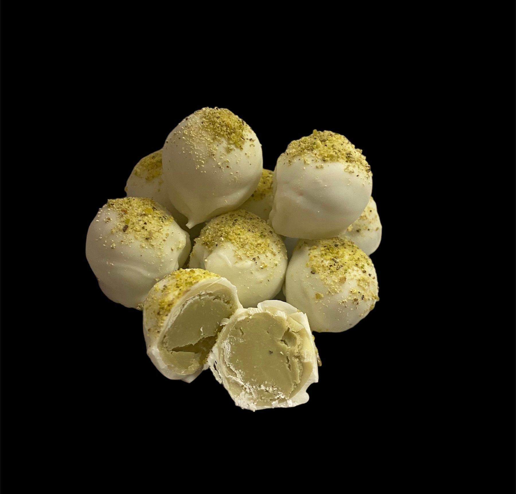 White powdered dessert balls stacked on black background, with one cut open to show creamy filling