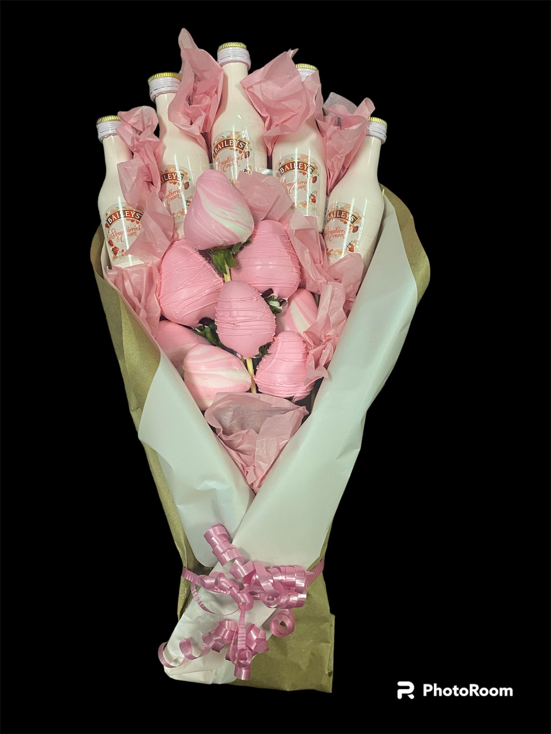 Bouquet of pink flowers wrapped in pale paper, tied with a pink ribbon