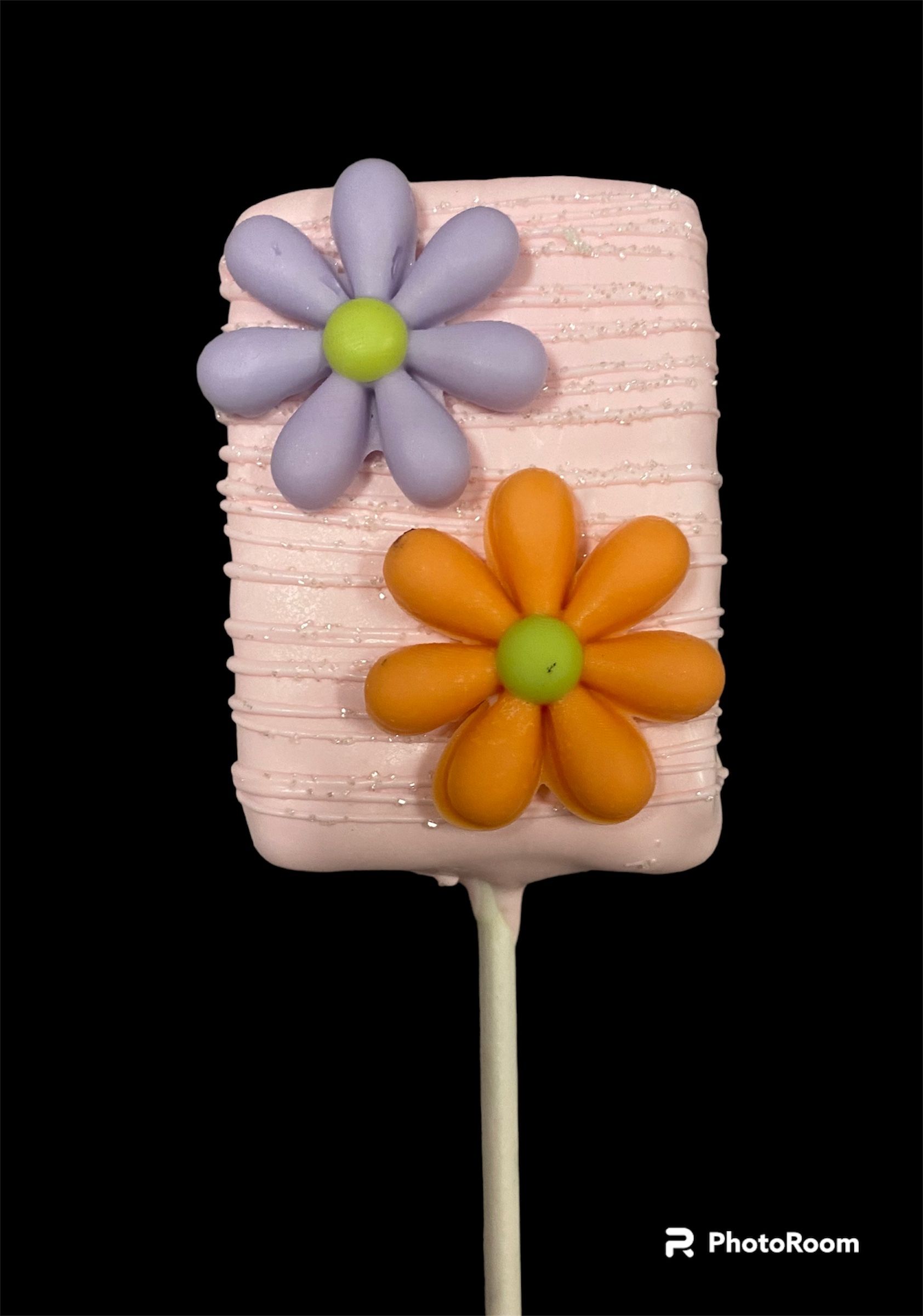 Pink popsicle decorated with purple and orange fondant flowers on a stick